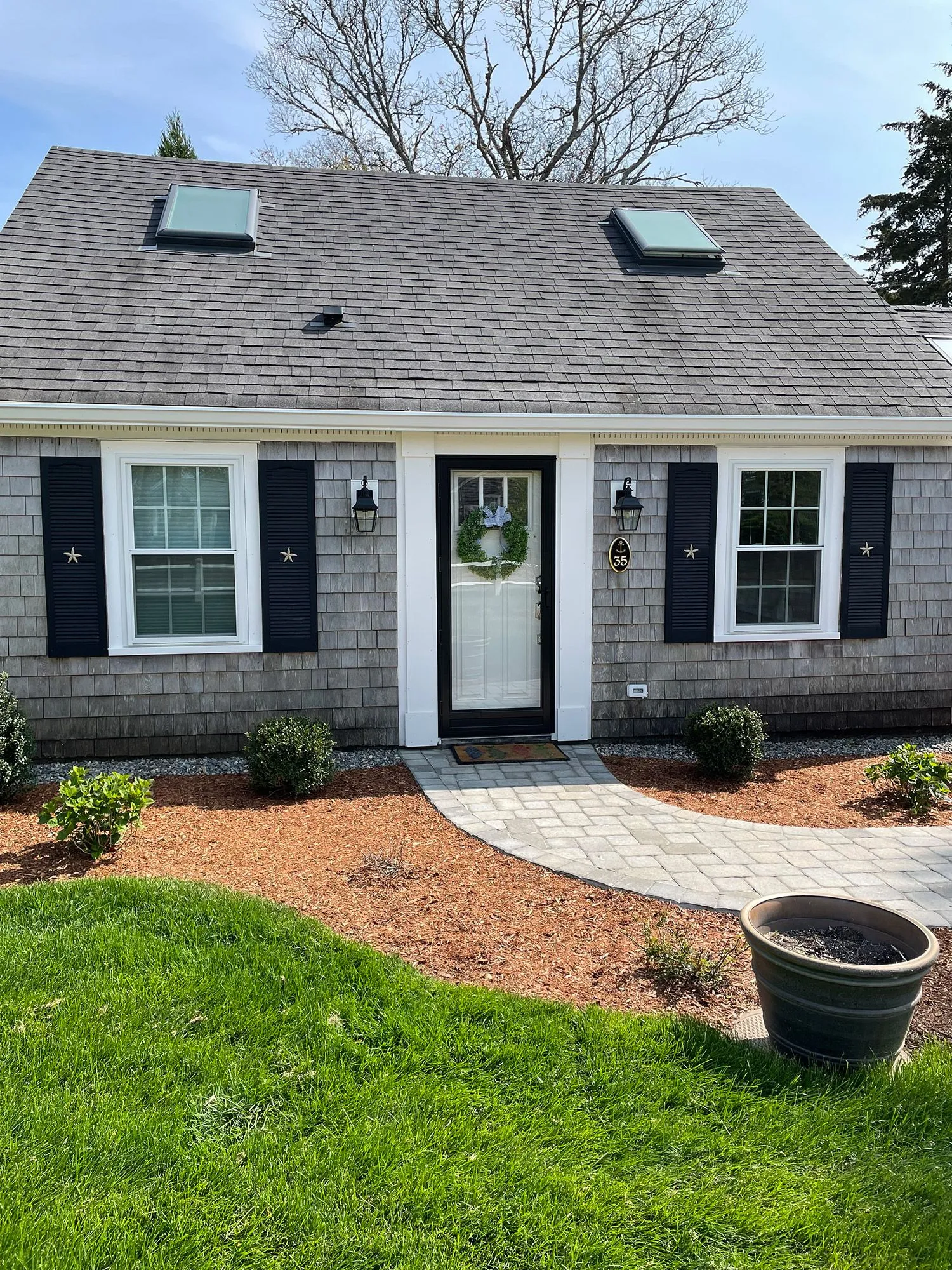 a small house with black shutters and a skylight on the roof