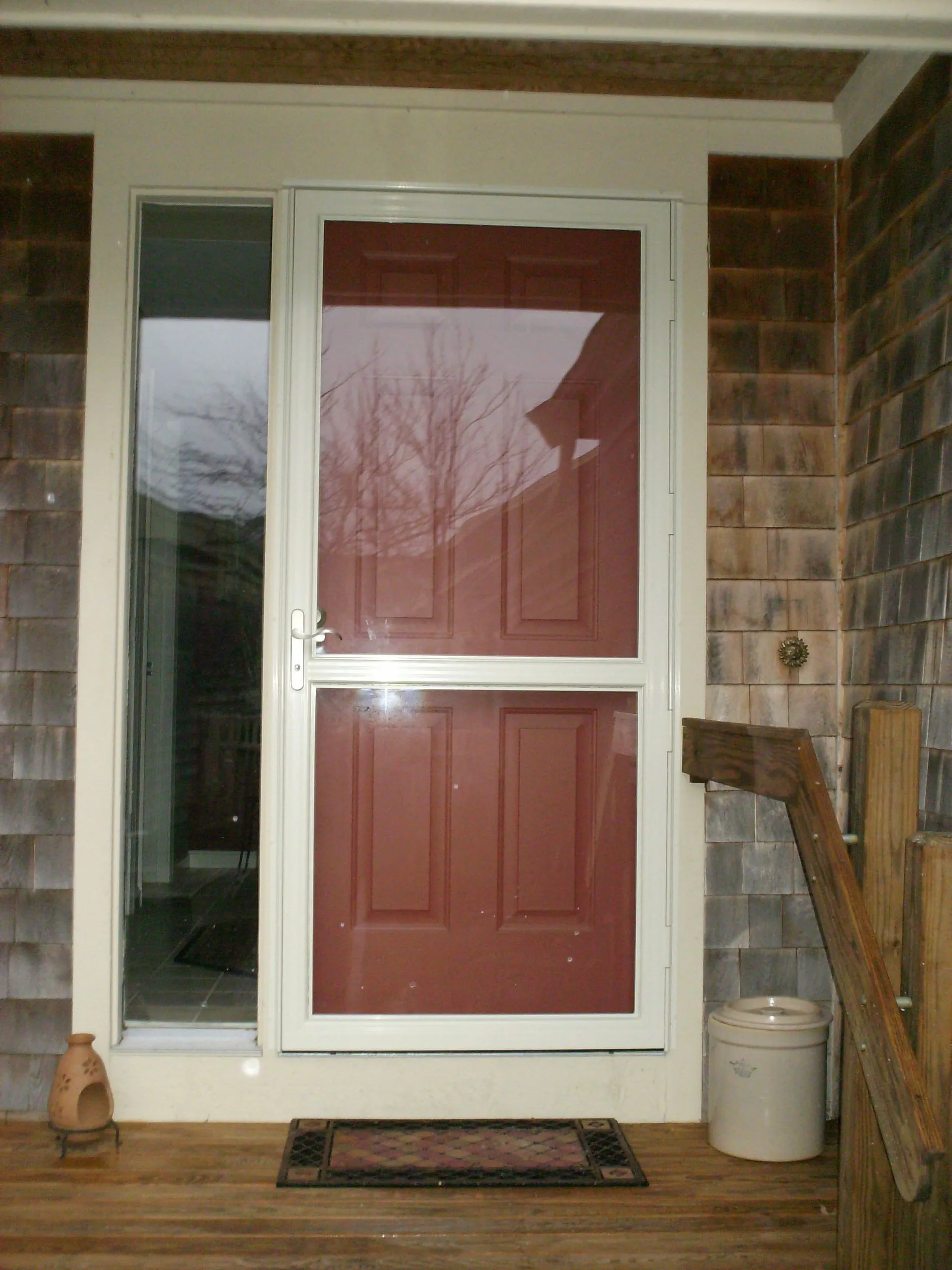 a red door with a screen is on a porch