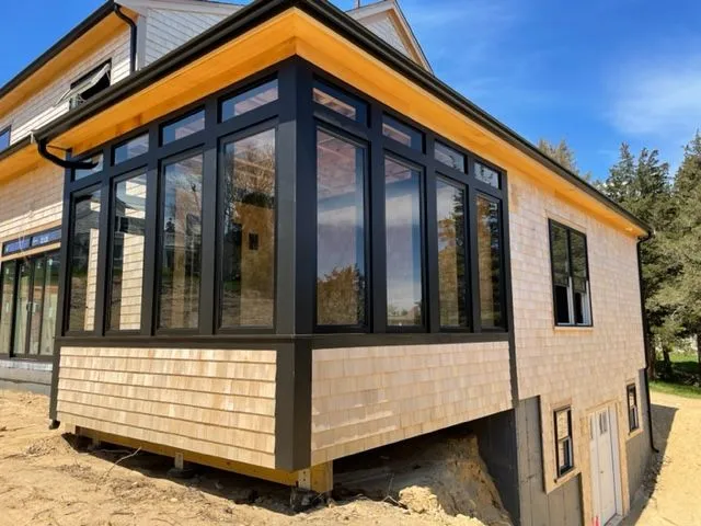a house with a lot of windows is sitting on top of a dirt hill