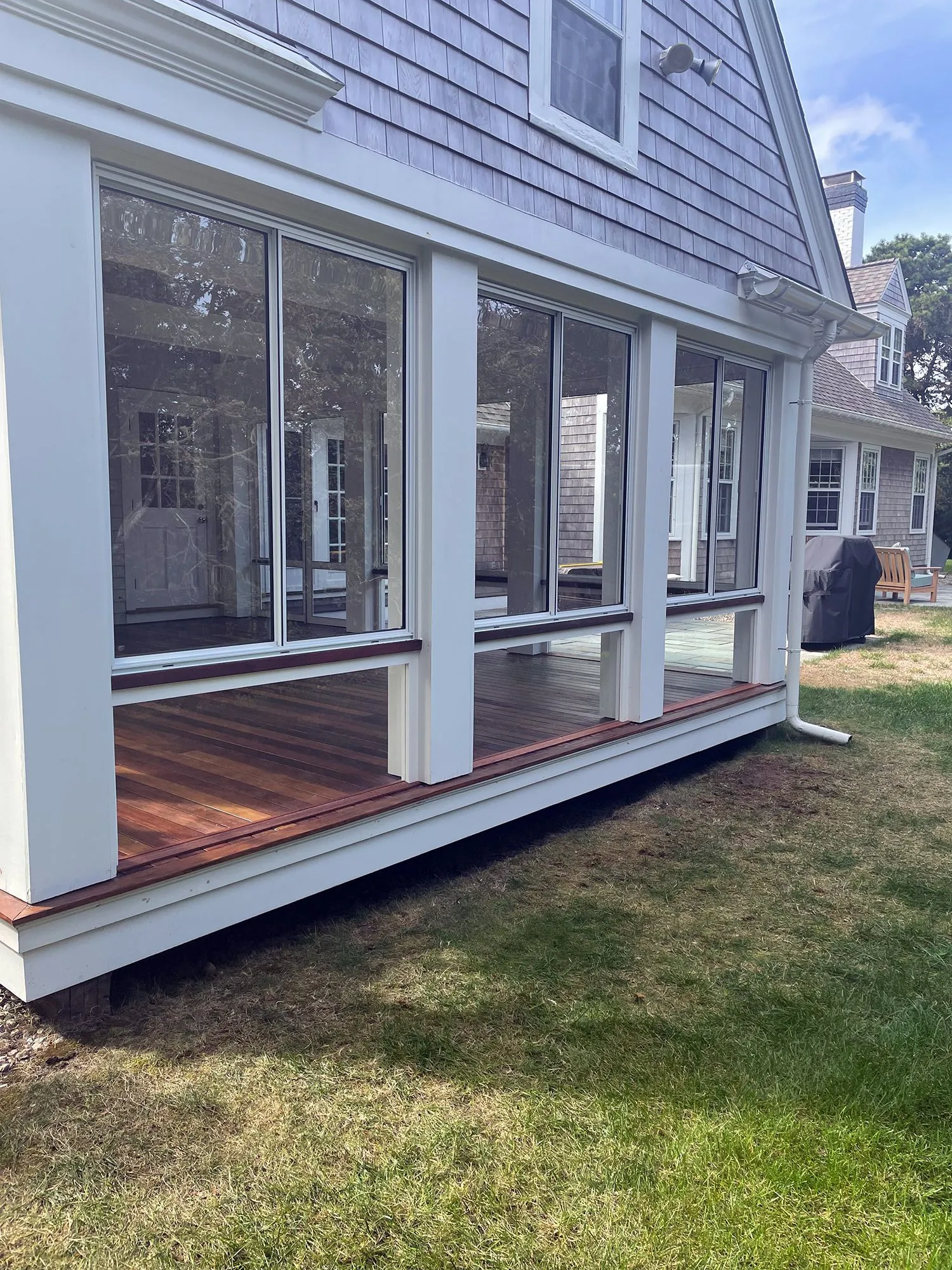 a screened in porch with a lot of windows on the side of a house