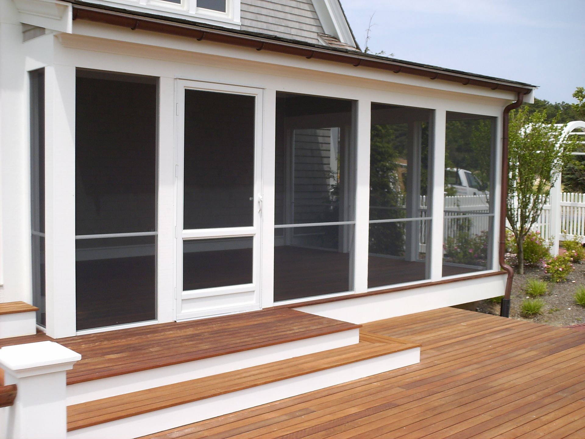 a screened in porch with a wooden deck and stairs