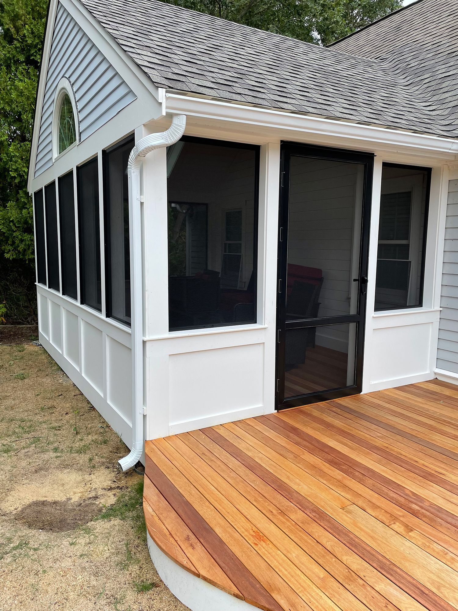 a screened in porch with a wooden deck next to a house