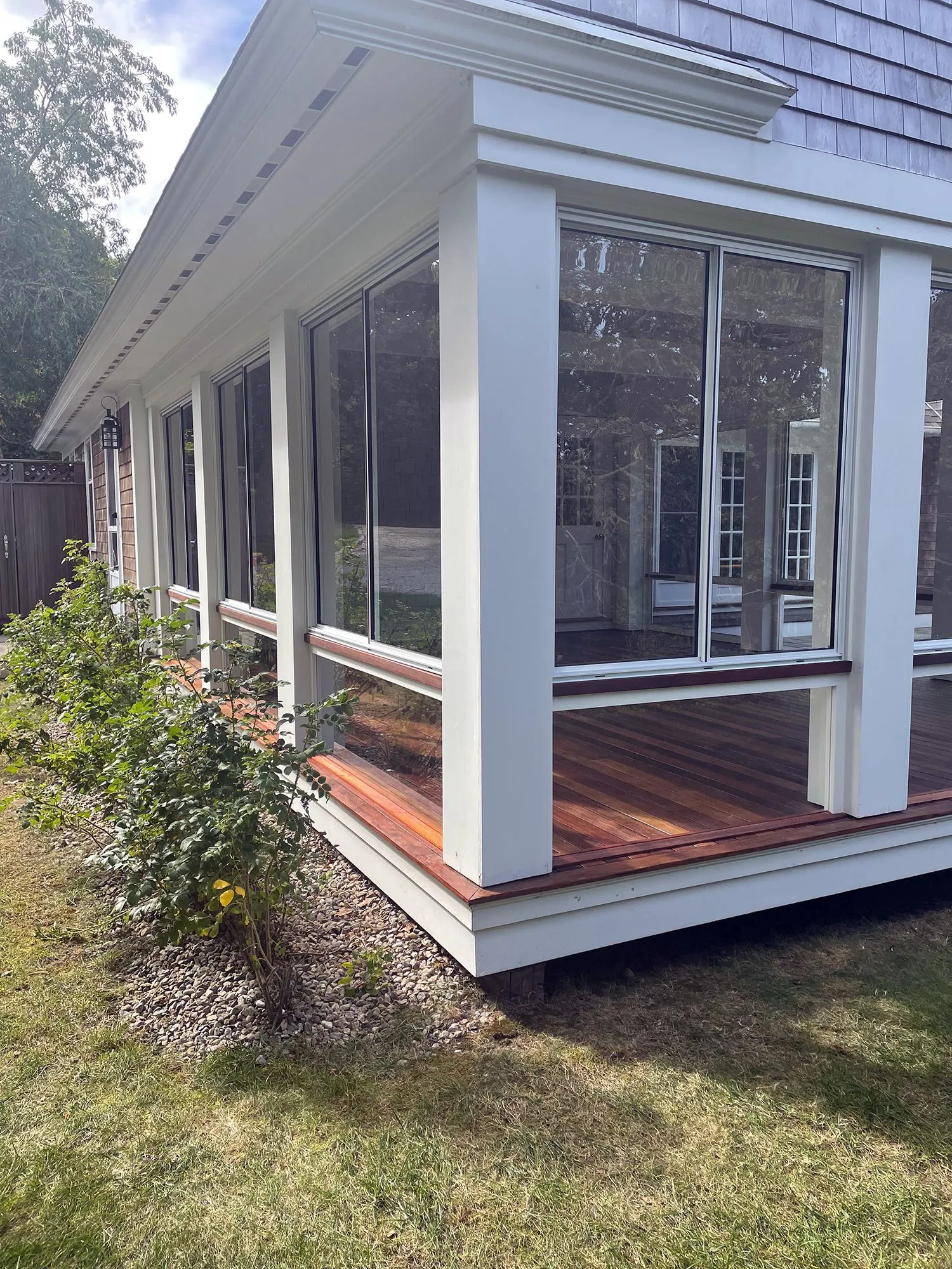 a screened in porch with a lot of windows and a wooden deck