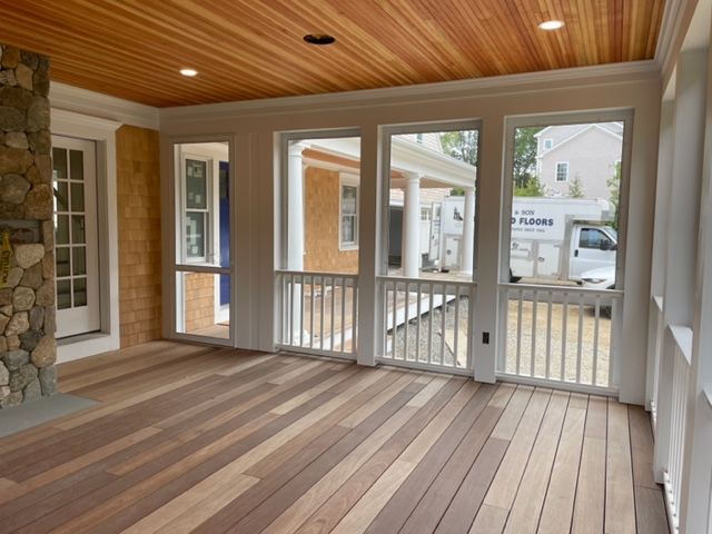 a screened in porch with lots of windows and wooden floors